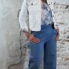 Luchtige bloemenblouse in jeansblauw met jeansblauw wijde pantalon en kort wit spijkerjasje, vrouwelijke look met hak.
