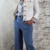 Luchtige bloemenblouse in jeansblauw met jeansblauw wijde pantalon en kort wit spijkerjasje, vrouwelijke look met hak.