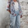 Bloemenblouse in blauw tinten op lichte denim, losvallend met opgerolde mouwen voor een casual uitstraling.