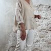 Linnen blouse zandkleur met opgerolde mouw, gecombineerd met ecru 3D-jeans en gouden sleehaksandaal – zijkant