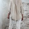 Achterkant linnen blouse zandkleur met opgerolde mouwen en langere achterkant – gedragen met ecru 3D-jean