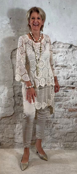 Gehaakte tuniek ecru met strakke glanzende stretch broek met koordsluiting en elastische tailleband.