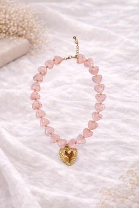 Roze korte halsketting met grote kralen in de vorm van hartjes en een gouden hart in het midden. Chunky hearts ketting Baboux